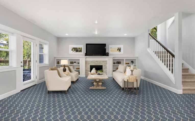 blue patterned carpet in family room with carpeted stairs 